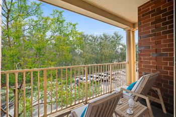 A balcony with a chair and a table with a cup on it.